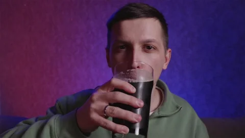 Satisfied man drinking beer from glass mug at night Stock Footage 333757073