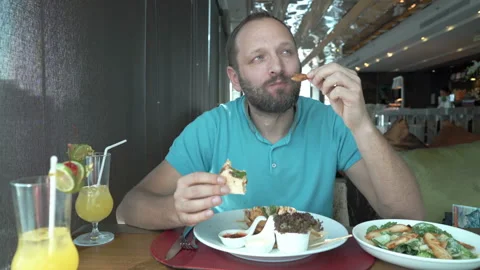 Satisfied man sitting in the restaurant and eating delicious meal Stock Footage 88575652