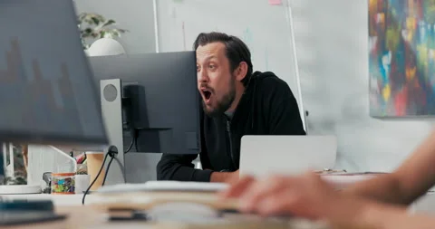 Satisfied office worker sitting in front of the computer monitor, happy to Stock Footage 164185170
