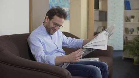 Satisfied principal reading newspaper, relaxed person sitting on sofa, press Stock Footage