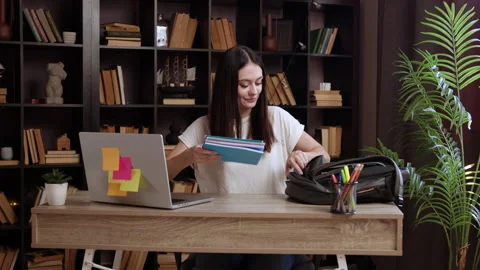 A satisfied student at an office table gathers her things and puts them in her Stock Footage 304929047