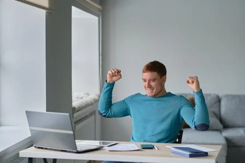 Satisfied with work done. Man working from home happily surprised looking at a Stock Photos