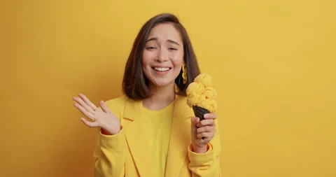 Satisfied young Asian woman eats appetizing ice cream gets pleasure from high Stock Footage 155484896