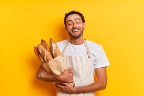 Satisfied young baker posing with a package of his own pastries, holds full Stock-Fotos