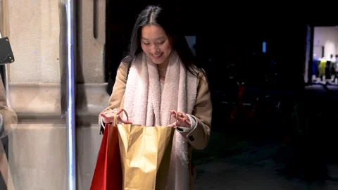 Satisfied young lady looking inside shopping bags in Christmas night Stock Footage 252808920