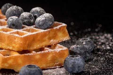 Satisfy your cravings with soft belgian waffles, blueberries, and sugar dust Stock Photos