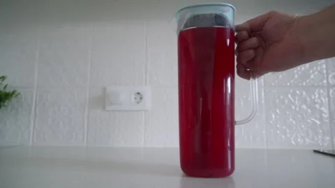 Satisfying Scrape: Hand Slides Refreshing Red Juice Jug on Kitchen Counter. Stock Footage 320809346