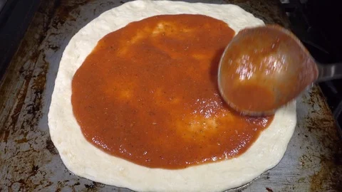 Sauce being spread on a pizza dough base. Video stock 108531107