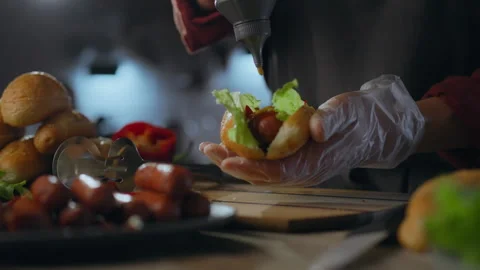 Sauce. Creative chef dressed in an apron preparing a hot dog with yellow mus Stock Footage 271146740
