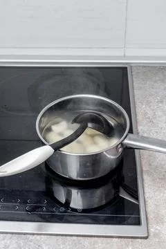 Saucepan on induction cooktop viewed through digital cooking interface displa Stock Photos