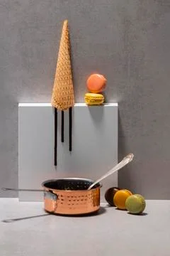 Saucepan with a spoon surrounded by assorted macaroons with an empty ice crea Stock Photos