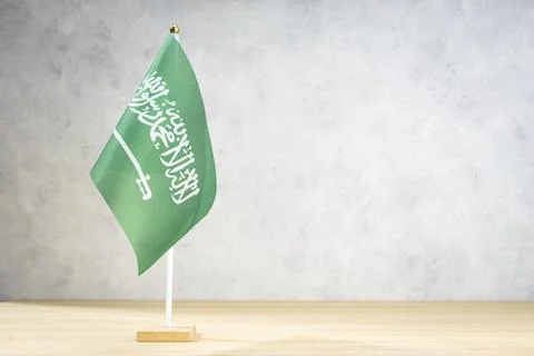 Saudi Arabia table flag on white textured wall. Copy space for text, designs or 스톡 일러스트