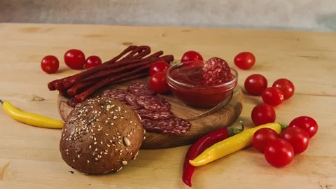 Sausage, chili, cherry tomatoes, bread on wooden table. Stock Footage 84000854