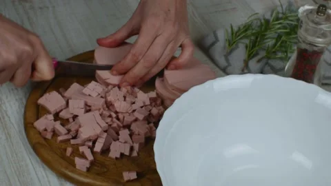 Sausage is cut into small pieces on cutting board with knife. Female hands close Stock Footage 234848094