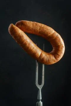 Sausage on fork on dark Fotos de archivo