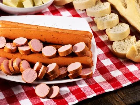 Sausage portion with baguette on table setting on checkered cloth 스톡 사진