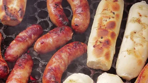 Sausages and garlic bread grilling on a hot barbecue, with visible smoke an.. 스톡 동영상 337941082