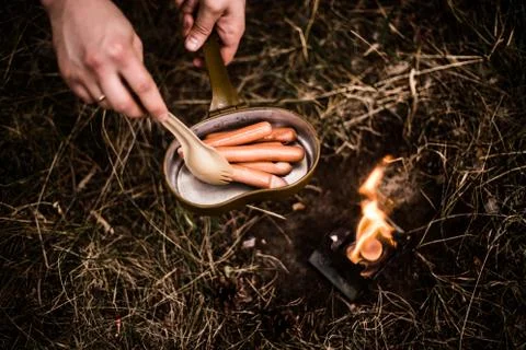 Sausages are fried over an open fire in a pan Stock Photos