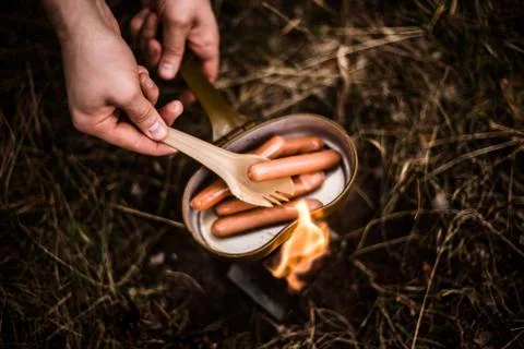Sausages are fried over an open fire in a pan Stock Photos