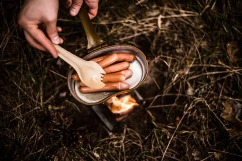 Sausages are fried over an open fire in a pan Stock Photos