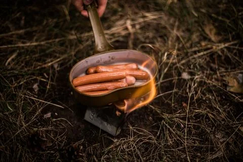 Sausages are fried over an open fire in a pan Stock Photos