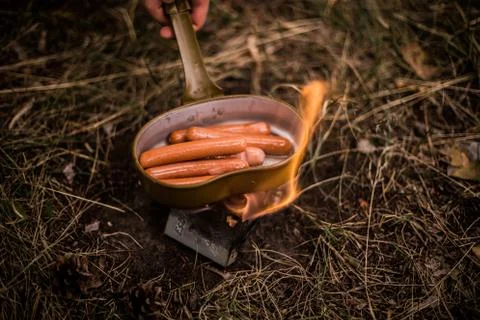 Sausages are fried over an open fire in a pan Stock Photos