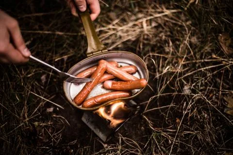 Sausages are fried over an open fire in a pan Stock Photos