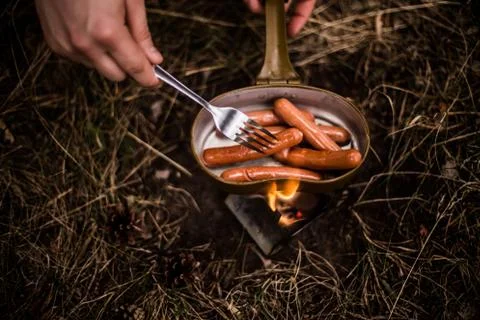 Sausages are fried over an open fire in a pan Stock Photos