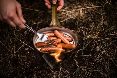 Sausages are fried over an open fire in a pan Stock Photos