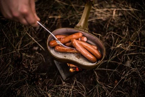 Sausages are fried over an open fire in a pan Stock Photos