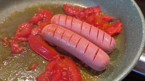 Sausages are fried with tomatoes in vegetable oil and a frying pan. 스톡 동영상 335726418