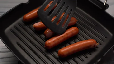 Sausages are turning with a spatula while frying on the grill pan. Bbq at home 4 動画素材 162481612