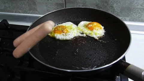 Sausages fall on the pan to the fried eggs in slow motion Stock Footage 102282791
