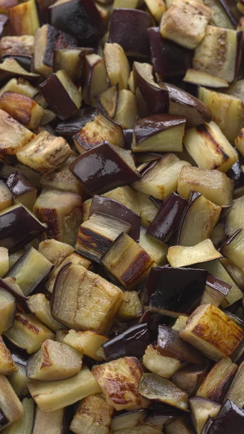 Sauteed aubergine chunks background texture. Table spin. Vertical video. Stock Footage 311566284