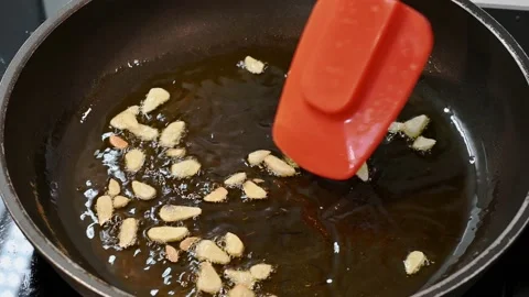 Sautéed sliced garlic in the pan Stock Footage 219875336