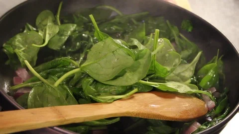 Sautéeing spinach with red onion Stock Footage 96475814