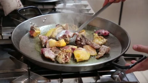 Sautéing meat and vegetables on the fire How to prepare a real Valencian paella 库存影片 153274397