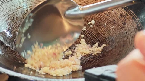 Sautéing minced garlic and shallots in a traditional wok close up. Видео 339078092