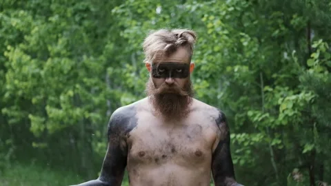 Savage with painted face, looking at camera, evil eyes, primeval times Stock Footage 131377998