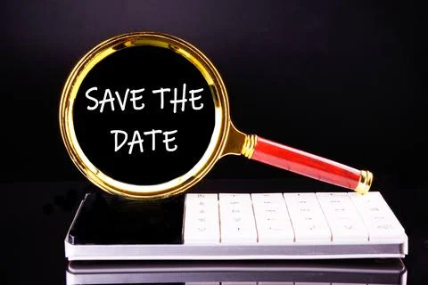 SAVE THE DATE words through a magnifying glass on a black background Stock Photos