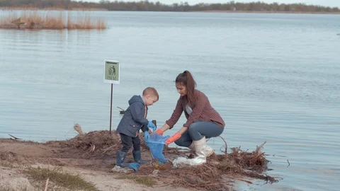 Save planet, young mother with son volunteers clean polluted beach from plastic Stock Footage 108170743
