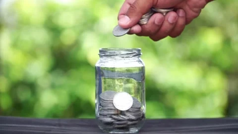 Saving 500 Rupiah coins in a clear glass jar Stock Footage 288351119