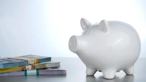 Saving Bitcoin cryptocurrency in white pig moneybox near Dollars and Euros on Stock Footage 88782590