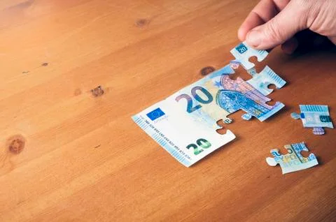 Saving concept: hand putting a piece on a 20 euro puzzle Stock Photos