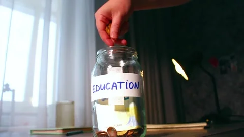 Saving for education fund using money jar. Young person carefully placing money Видео 330588747