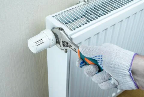 Saving energy resources. hand with an adjustable wrench regulates heat on hea Stock Photos