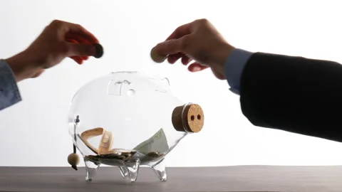 Saving for the family - several hands throw coins into a glass piggy bank Stock Footage 130396915