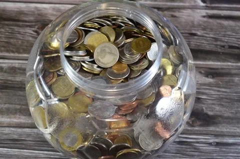 A saving jar with various coins from different countries from the world, vi.. Stock Photos