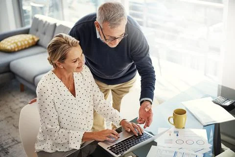 Saving keeps their retirement secure. a mature couple using a laptop while going Stock Photos