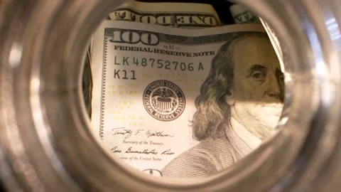 Saving money, 100 dollars inside glass jar Stock Footage 144242690